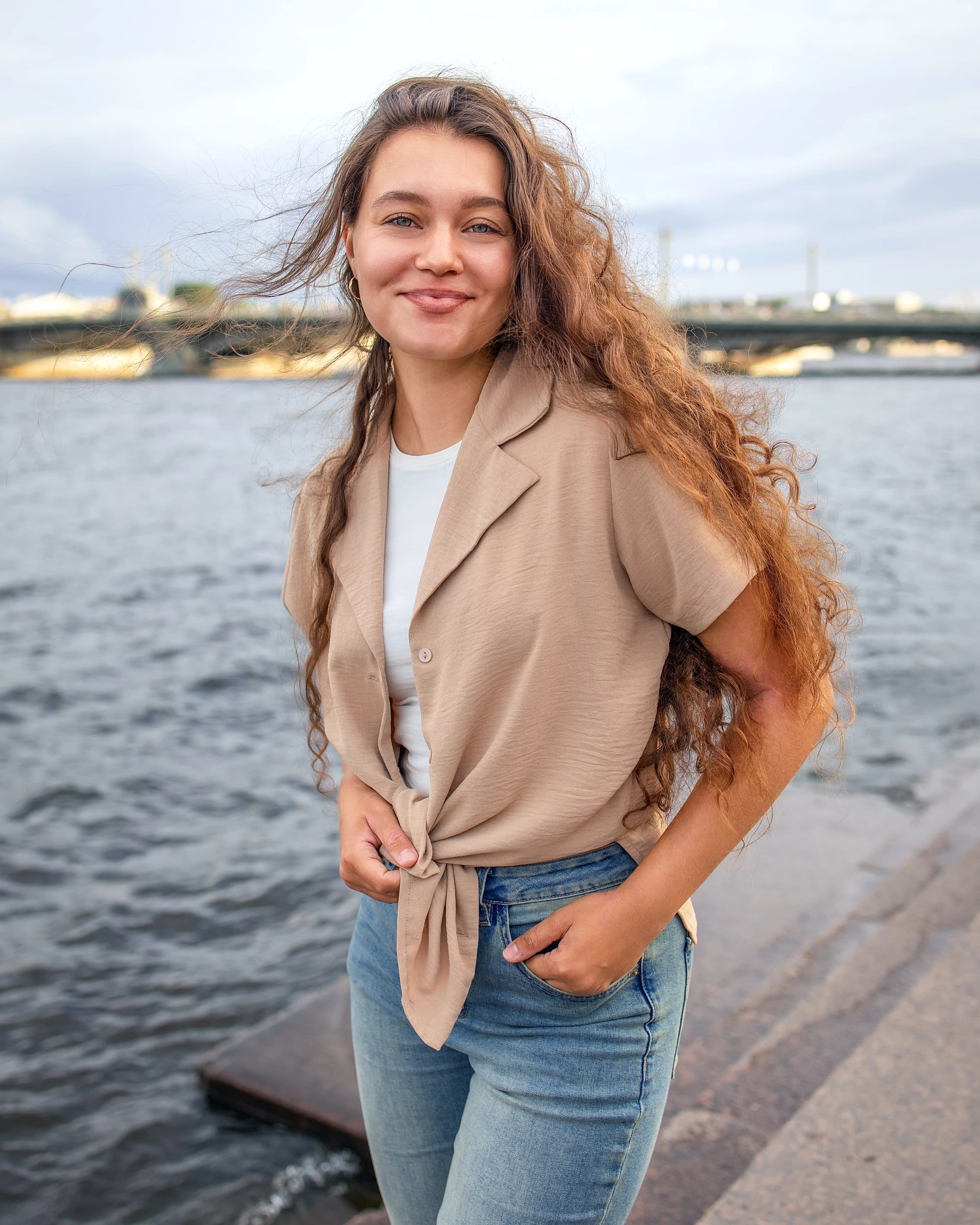 Smiling lady with curly hair standing by river