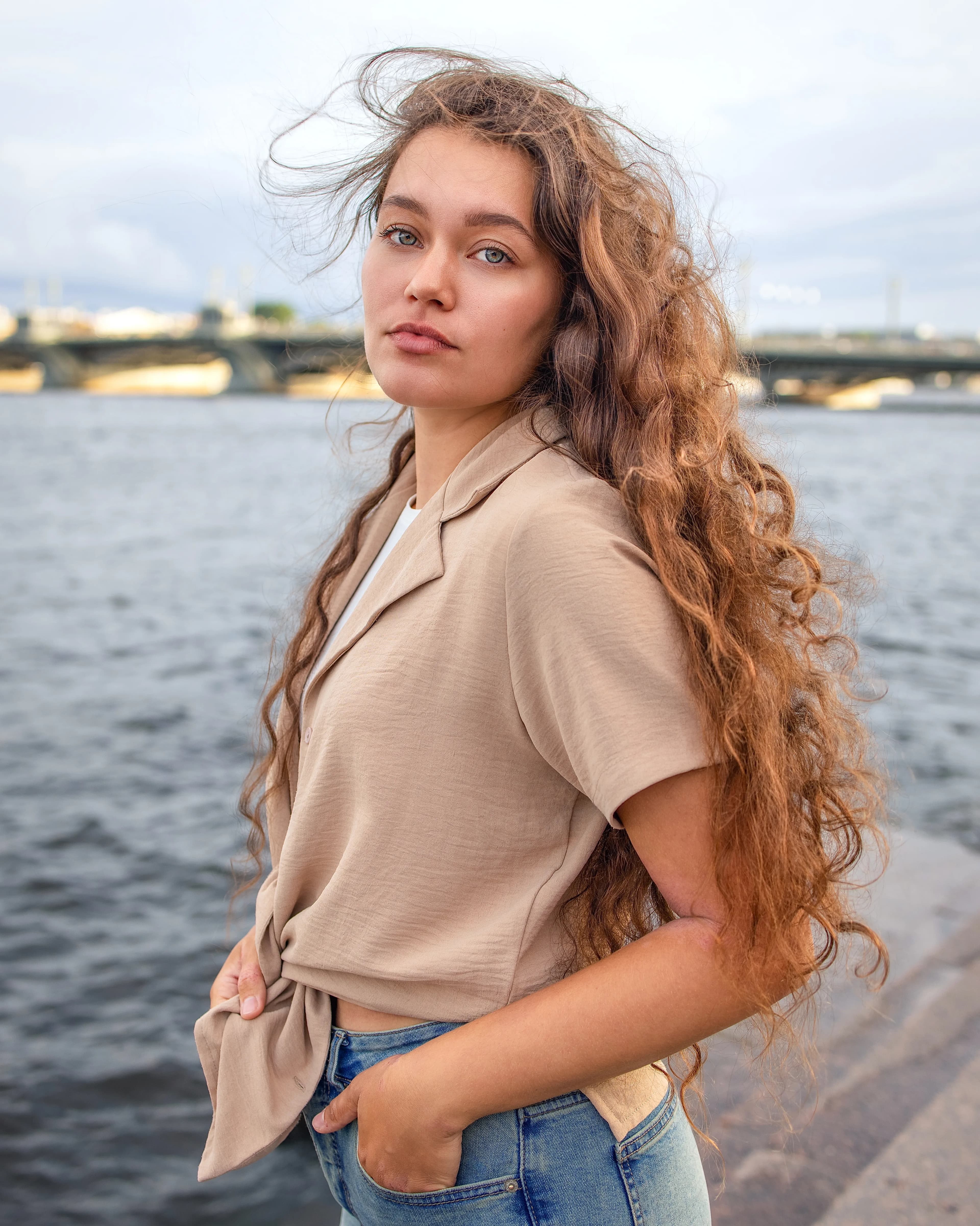 Lady with curly hair standing sideways by river